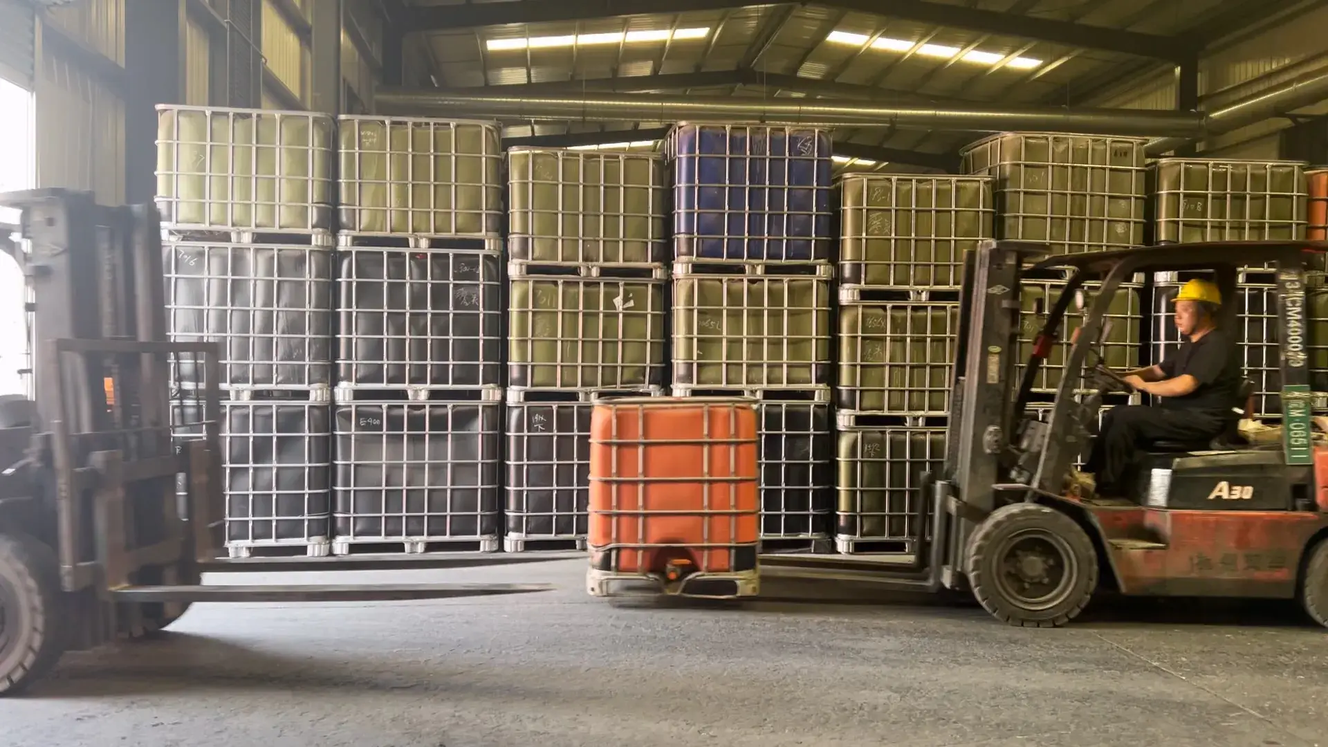 A forklift moving barrels of resin in the spacious logistics warehouse